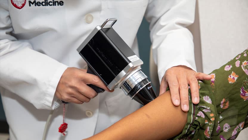 Dermatologist using tool to inspect skin of patient