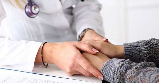 Image of caregiver holding patient's hands, supportive oncology