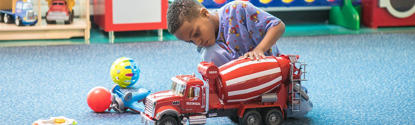 Comer patient playing with a fire truck in the playroom