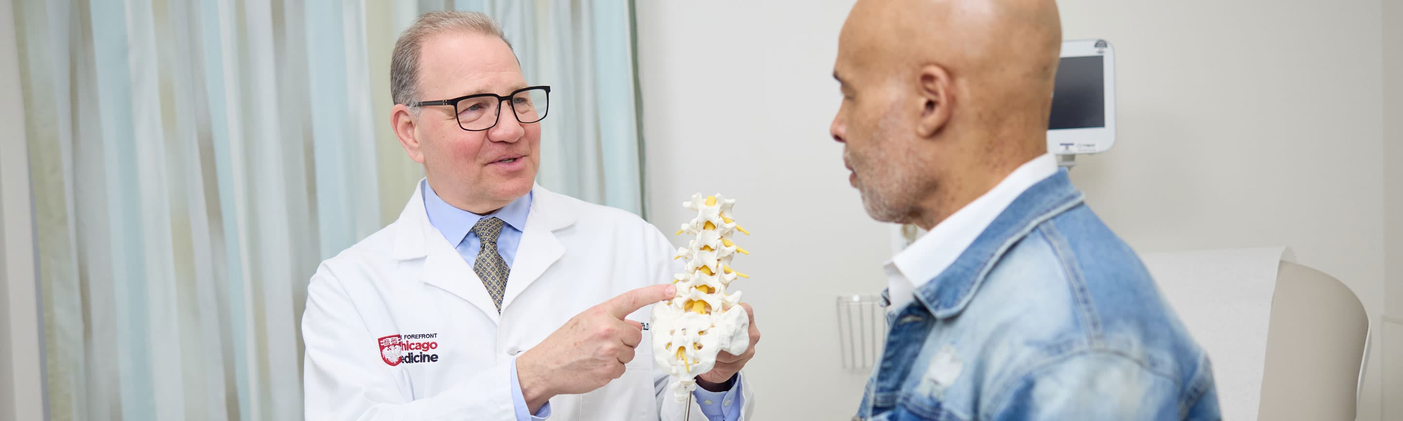 Martin Herman, MD, neurosurgeon and spine expert, with patient in clinic