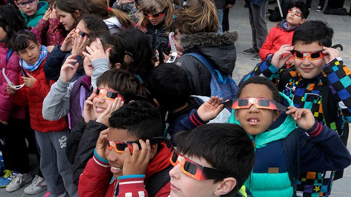 Children watch a solar eclipse with safety glasses